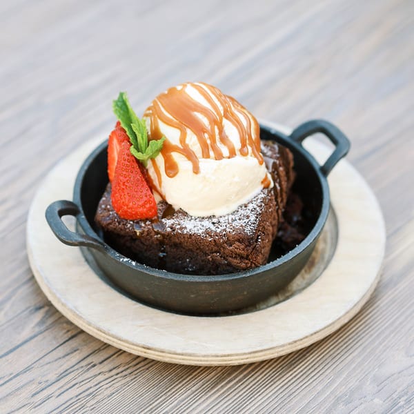 Rustik Fork's warm brownie with vanilla ice cream, caramel, strawberry, and mint in a skillet.